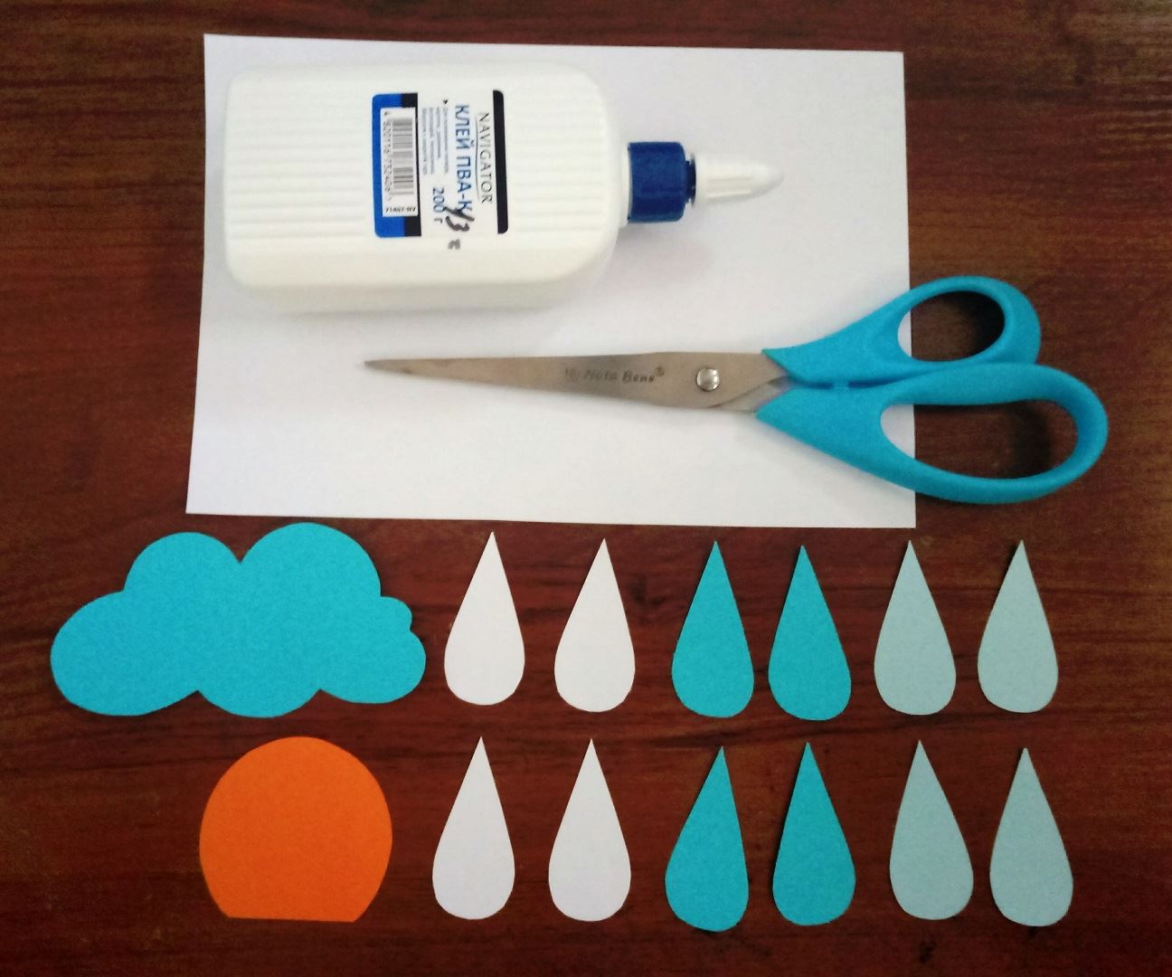 First we cut out droplets of white, blue and dark blue paper. Then a circle with a cut edge and a cloud.