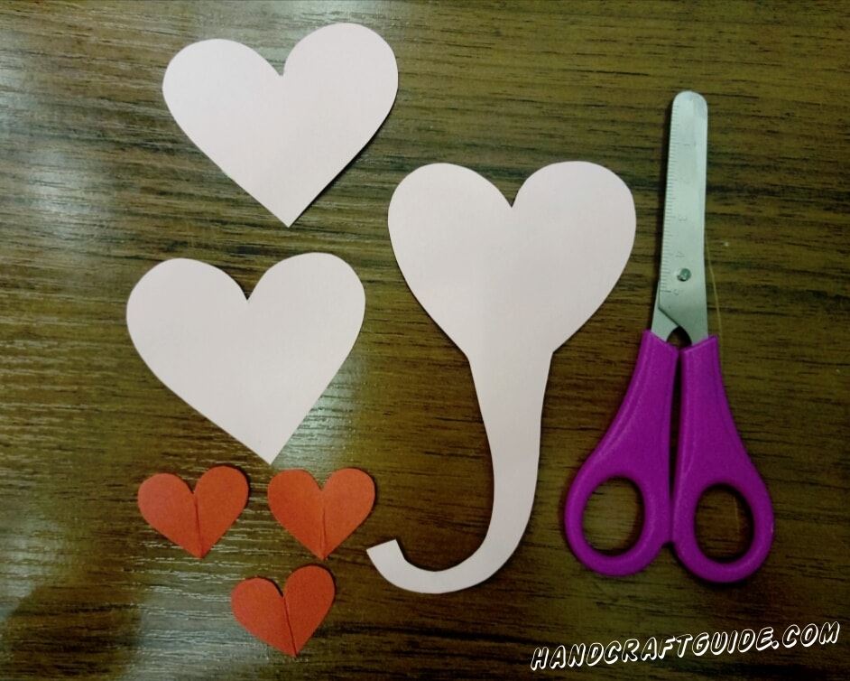 First, we cut out 3 small hearts from red paper, 2 large ones from pink and one of the same size, only with a proboscis on the sharp end.
