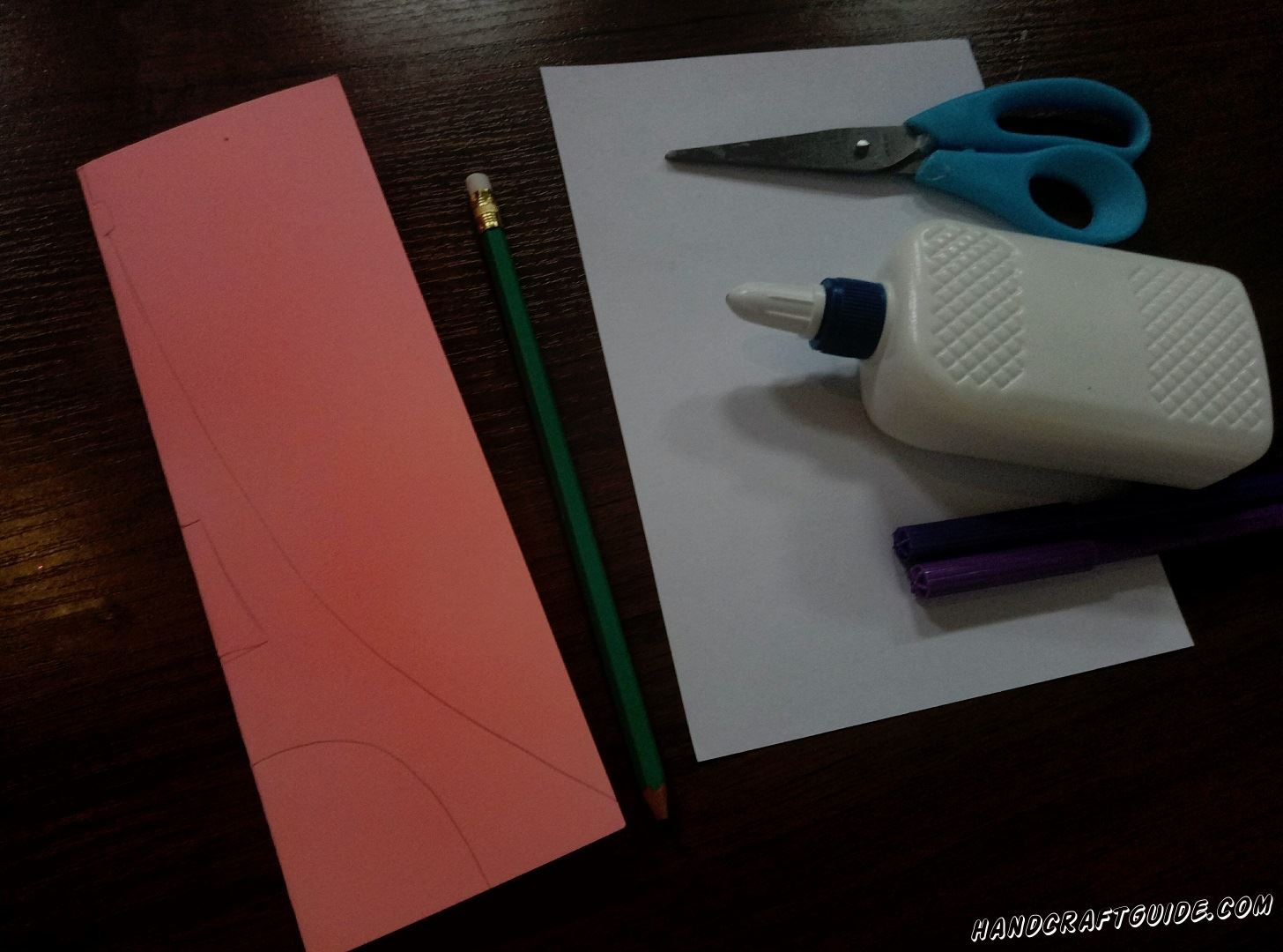 At the very beginning take a pink sheet of paper and vertically fold it in half . Then draw a half of the tower so that when you cut it out, you'll get a symmetrical figure.