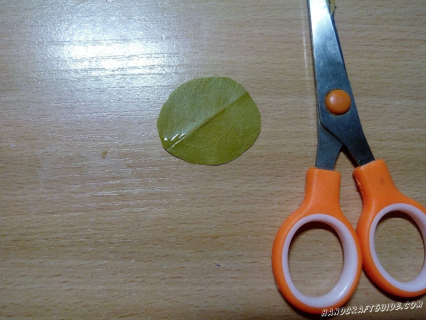 Берем круглый осенний листочек и намазываем один краюшек клеем. Приклеиваем длинный листик с дерева