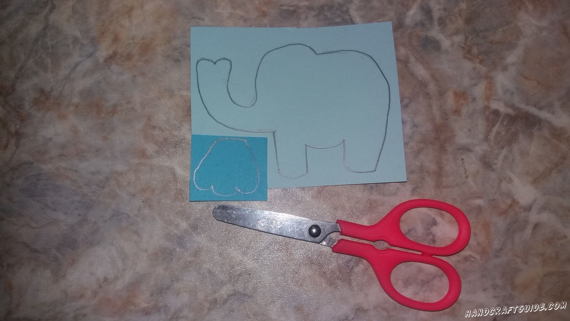 На голубом листе бумаги мы рисуем и вырезаем образ слона. На синей бумаге мы рисуем ушко слона и также вырезаем нарисованную картинку. 