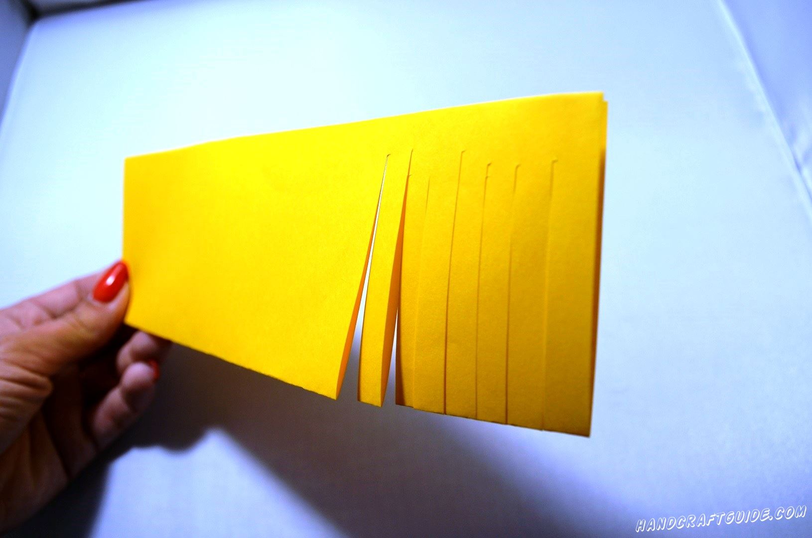 Берем лист желтой бумаги и складываем его вдоль пополам и начинаем делать надрезы со стороны сгиба и не до конца противоположной.