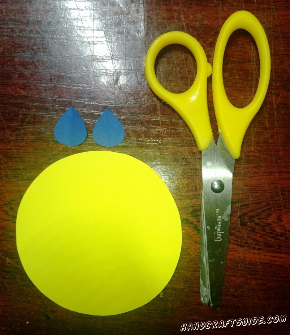 Вырезаем большой бумажный круг желтого цвета и две капельки из голубой бумаги